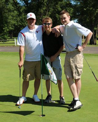 1 teacher and 2 students posing for a picture on the golf course.