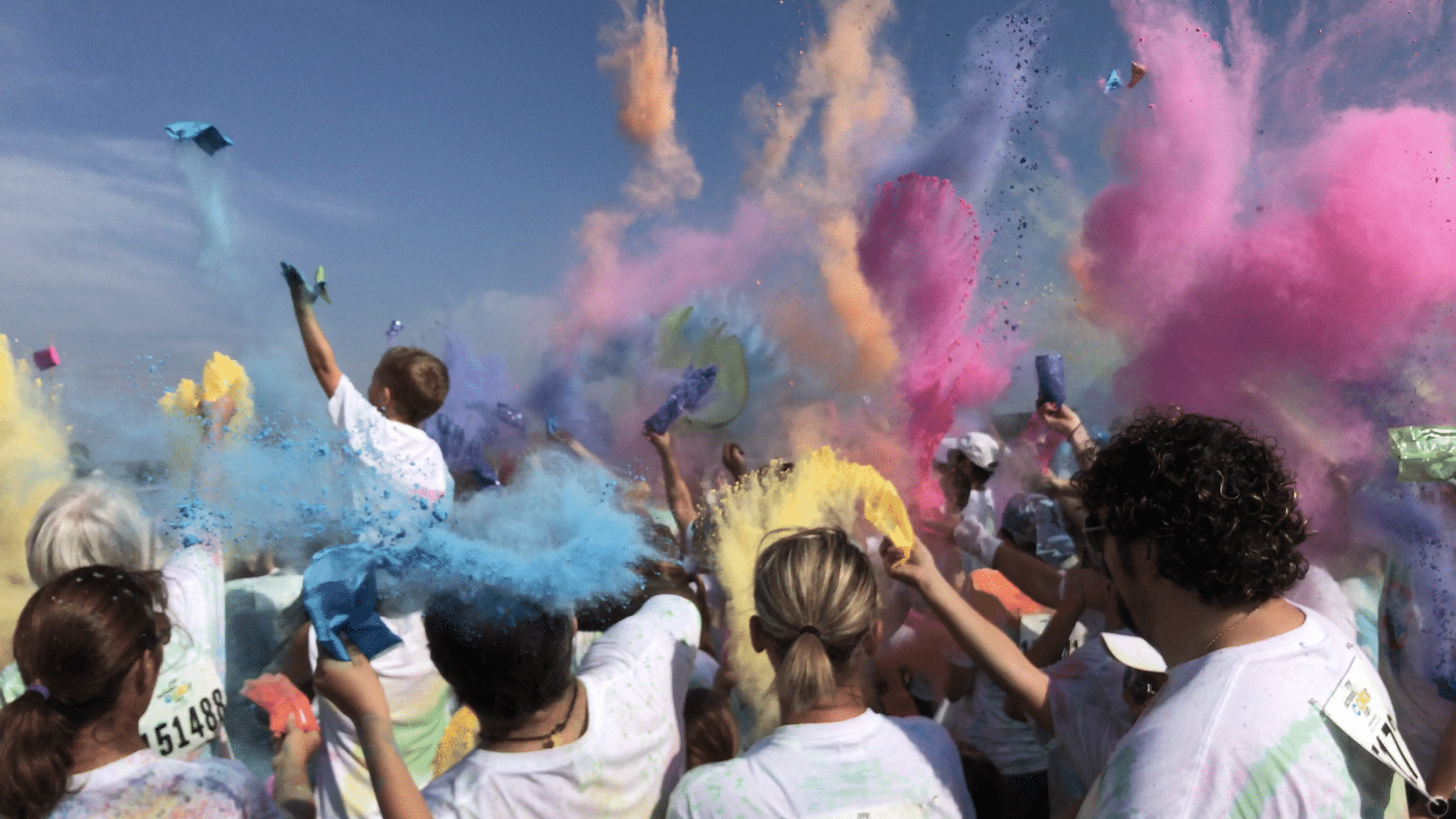 Students and parents throwing color packets during the Color Run color celebration