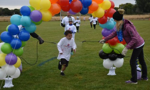 Students running through a balloon arch during the school's color run.