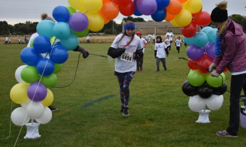 Students running through a balloon arch during the school's color run.