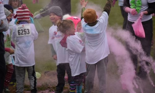 Elementary students throwing color packets during the school's color run.