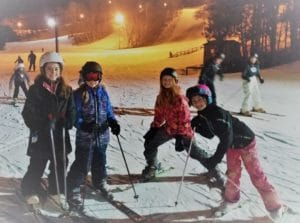 Four female student posing for a picture at Trollhaugen during ski club.
