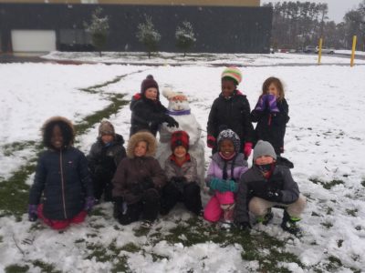 Ms. Parsons first grade students at recess in the snow with their snowman